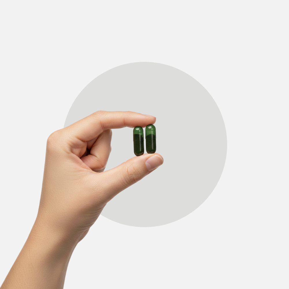 Two green capsules held between fingers
