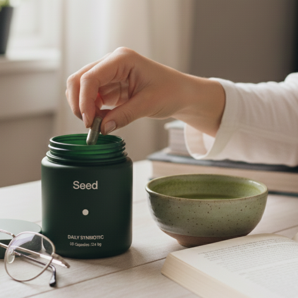A hand taking a capsule from the jar beside a bowl of matcha